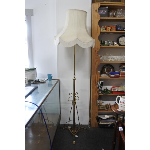 569 - A brass standard lamp and shade on tripod base, measuring 76