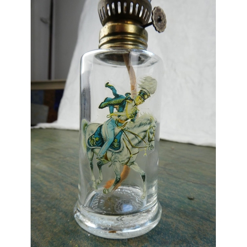 128 - A small clear glass oil lamp with a picture of a soldier on horseback.