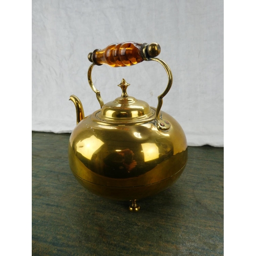 63 - An antique brass kettle with amber glass handle.