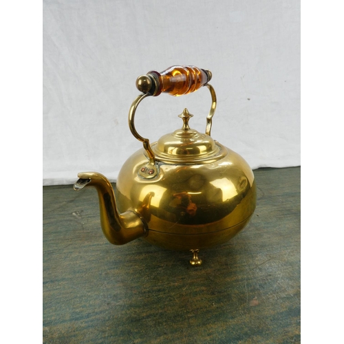 63 - An antique brass kettle with amber glass handle.