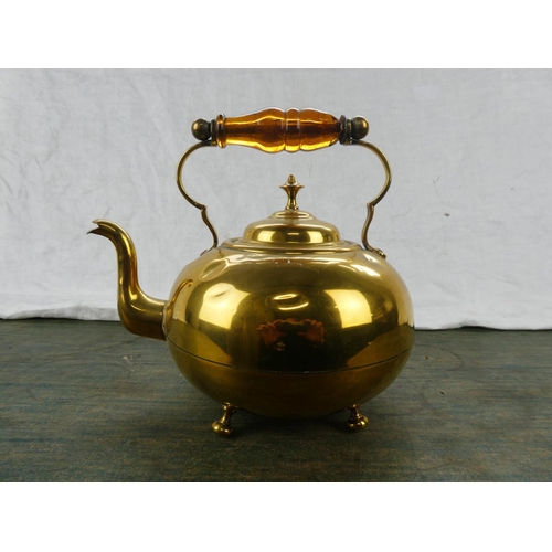 63 - An antique brass kettle with amber glass handle.