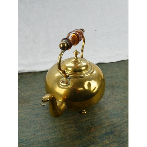 63 - An antique brass kettle with amber glass handle.