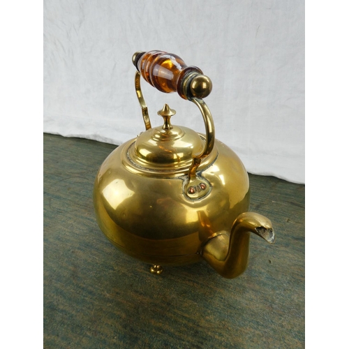 63 - An antique brass kettle with amber glass handle.