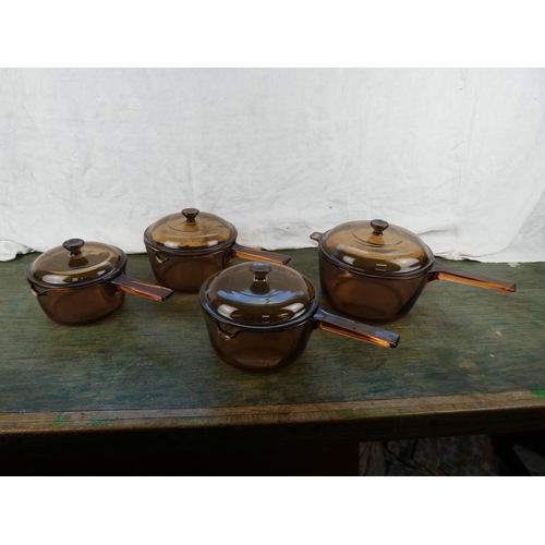 309 - Four vintage Corning glass lidded saucepans.