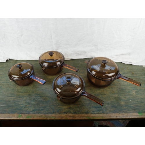 309 - Four vintage Corning glass lidded saucepans.