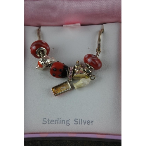 607 - A sterling silver child's bracelet with colourful charms.