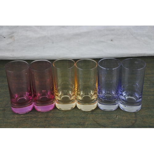 940 - A set of six coloured shot glasses.