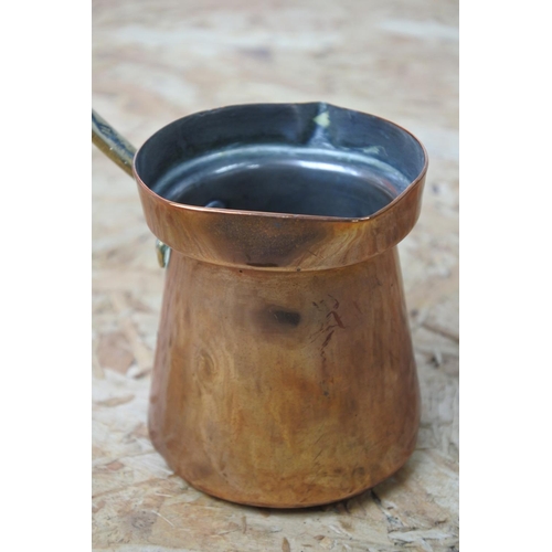 299 - A vintage copper and brass handled small pot.