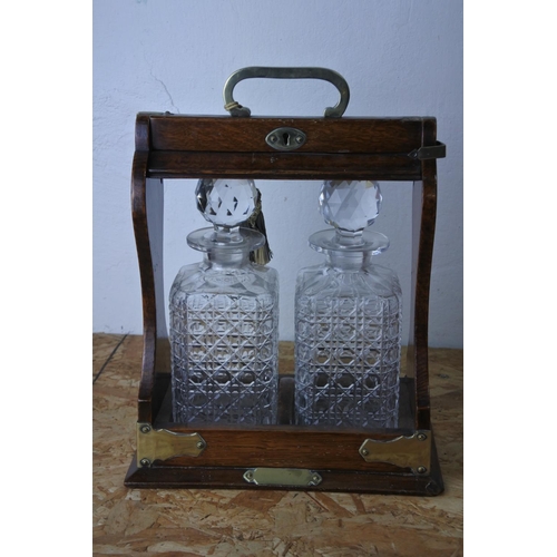 445 - A stunning antique oak cased tantalus with two glass decanters. (lacking key)