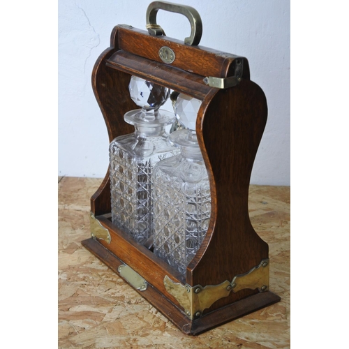 445 - A stunning antique oak cased tantalus with two glass decanters. (lacking key)