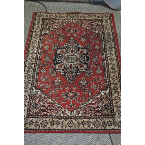 745 - A red and cream patterned floor rug.