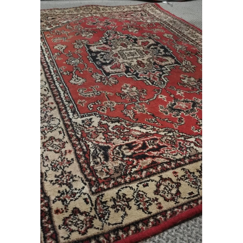 745 - A red and cream patterned floor rug.