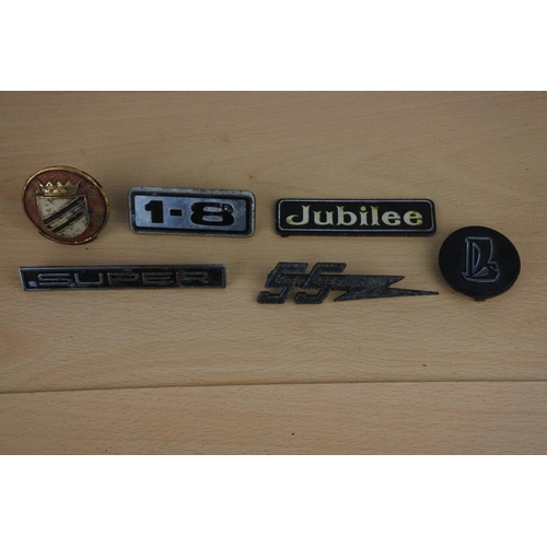 24 - A collection of car badges to include Jubilee and more.