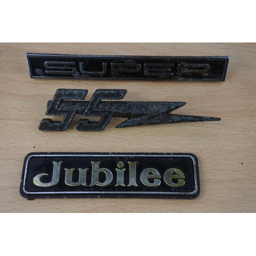 24 - A collection of car badges to include Jubilee and more.