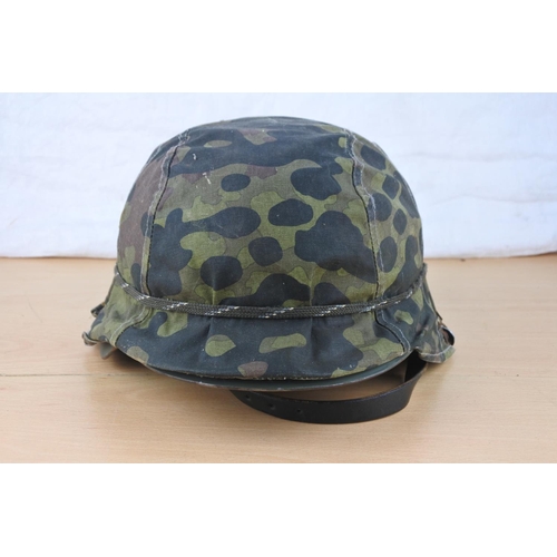 492 - A military helmet with camouflage cover.