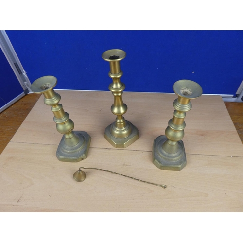 505 - Three brass candlesticks and a brass candle snuffer.