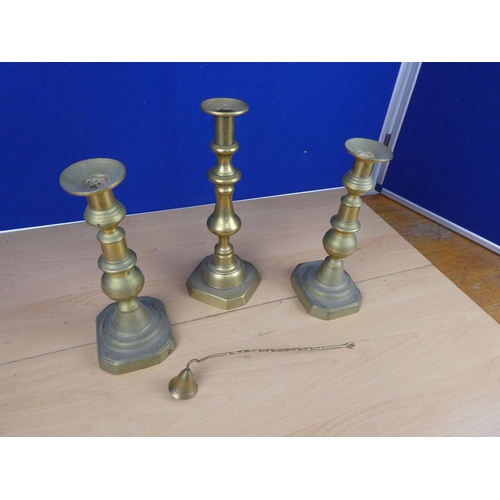 505 - Three brass candlesticks and a brass candle snuffer.