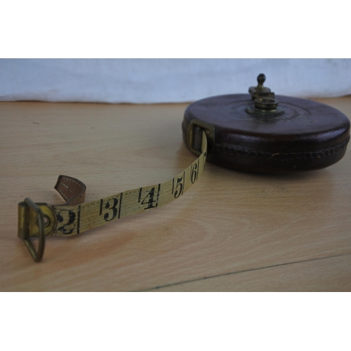 602 - A vintage leather cased Hockley & Abbey tape measure, a miniature magnifying glass and more.