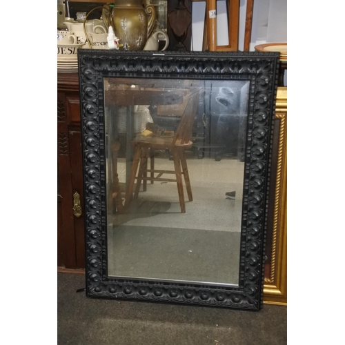 91 - A decorative black framed wall mirror. Approx 67x94cm.