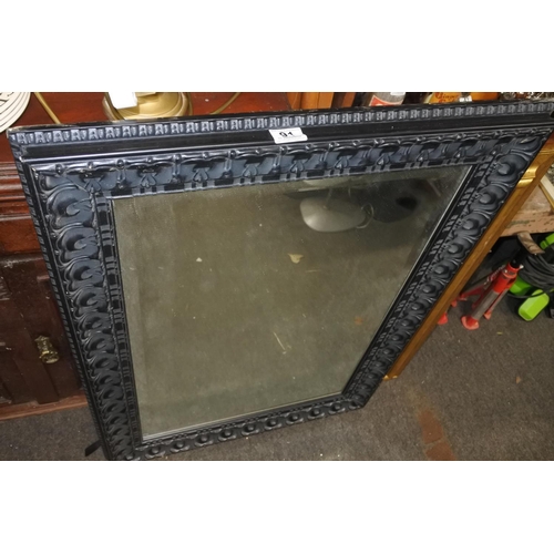 91 - A decorative black framed wall mirror. Approx 67x94cm.