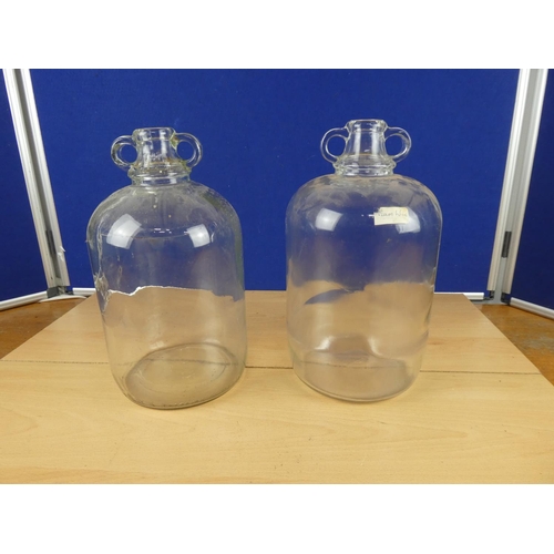 616 - Two clear glass demijohn bottles.