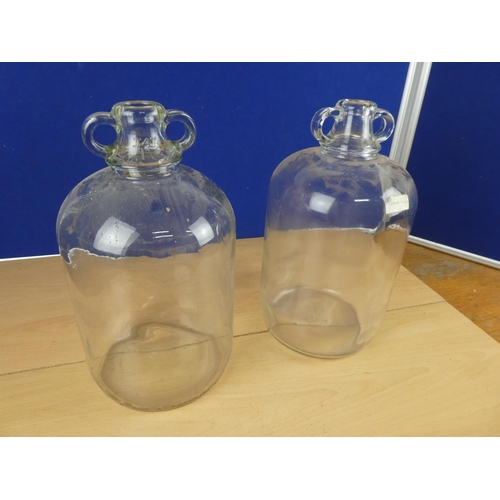 616 - Two clear glass demijohn bottles.