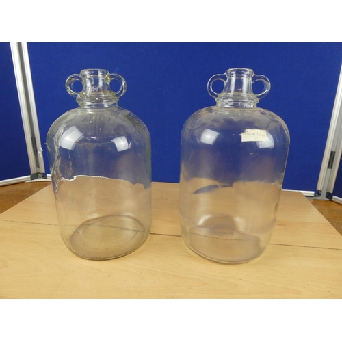 616 - Two clear glass demijohn bottles.