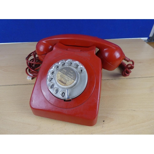 97 - A vintage red rotary telephone.