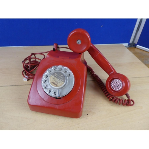 97 - A vintage red rotary telephone.