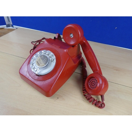 97 - A vintage red rotary telephone.