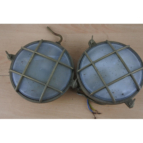 524 - Two vintage brass cased nautical lights, each measuring 15cm in diameter.