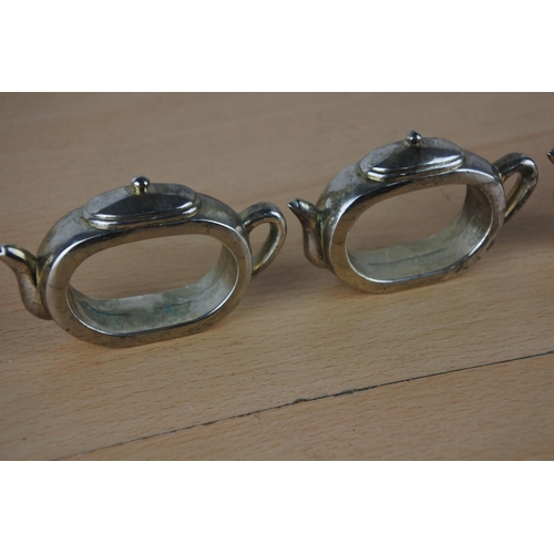 44 - Four metal teapot napkin rings.