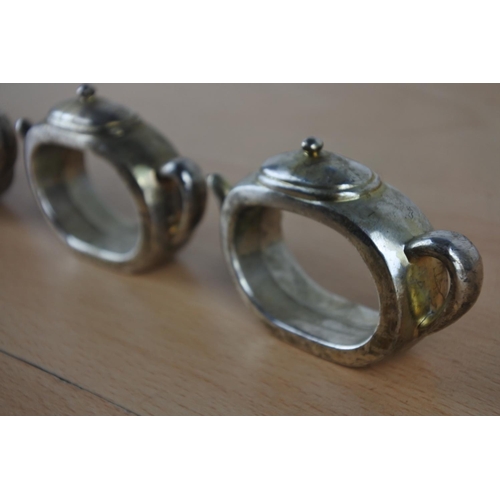 44 - Four metal teapot napkin rings.