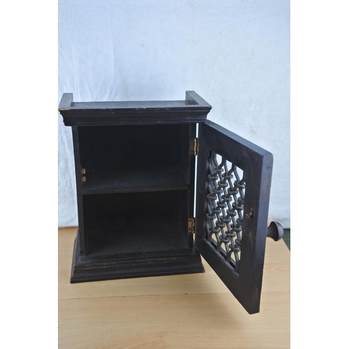 454 - A small wooden storage cupboard with cast iron lattice door. Approx 35cm.