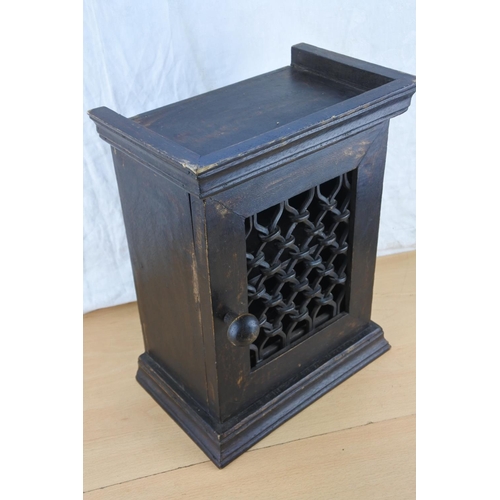 454 - A small wooden storage cupboard with cast iron lattice door. Approx 35cm.