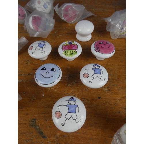 521 - A bag of assorted enamel character furniture knobs and more.