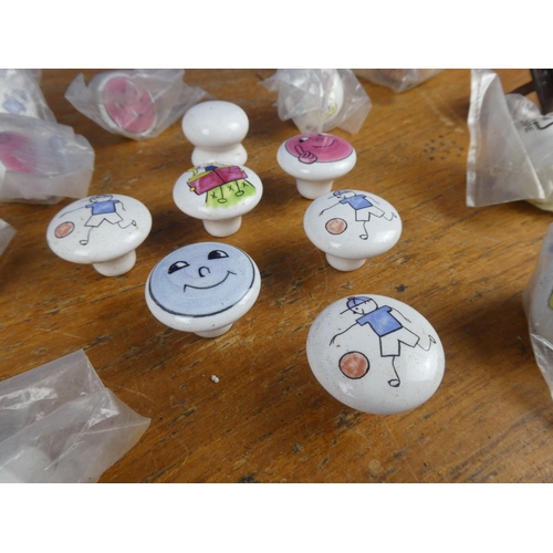 521 - A bag of assorted enamel character furniture knobs and more.