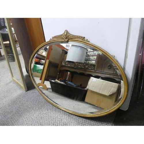 565 - An antique oval wall mirror with a gilt metal frame.  Approx  50x70cm.