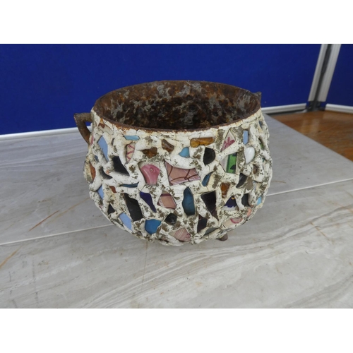 913 - An antique cast iron three legged pot decorated with coloured cut glass and ceramics.