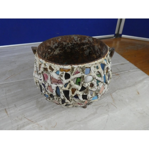 913 - An antique cast iron three legged pot decorated with coloured cut glass and ceramics.