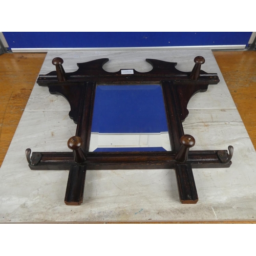 1052 - An oak framed wall mirror with clothes hooks.