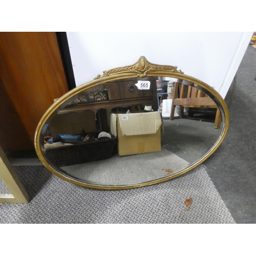 565 - An antique oval wall mirror with a gilt metal frame.  Approx  50x70cm.