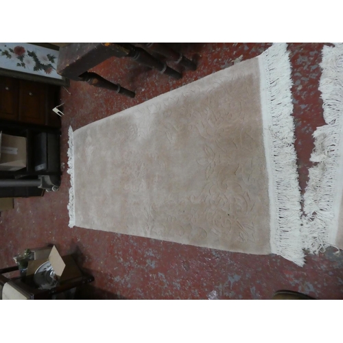 1269 - A cream patterned floor rug.