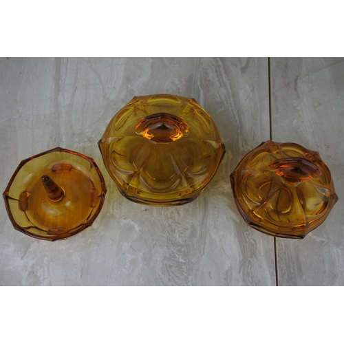 672 - A vintage three piece amber glass dressing table set.