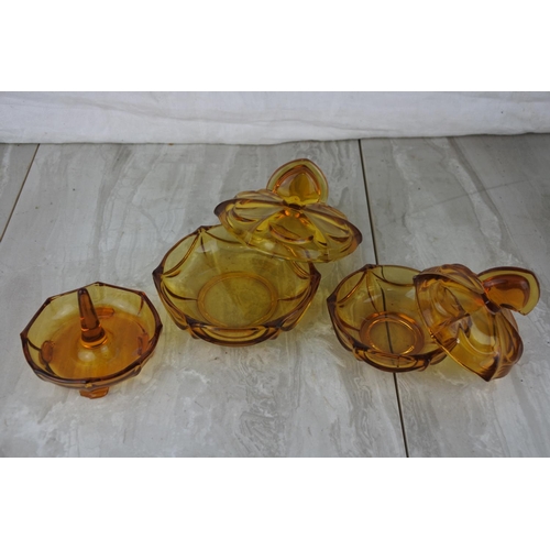 672 - A vintage three piece amber glass dressing table set.