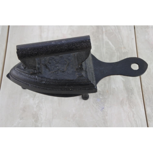 55 - An antique cast iron iron and stand.