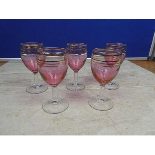 105 - A set of five ruby and gilt sherry glasses.