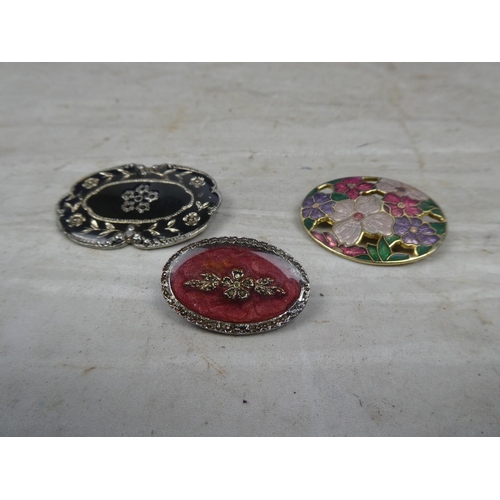 156 - Three floral patterned brooches.