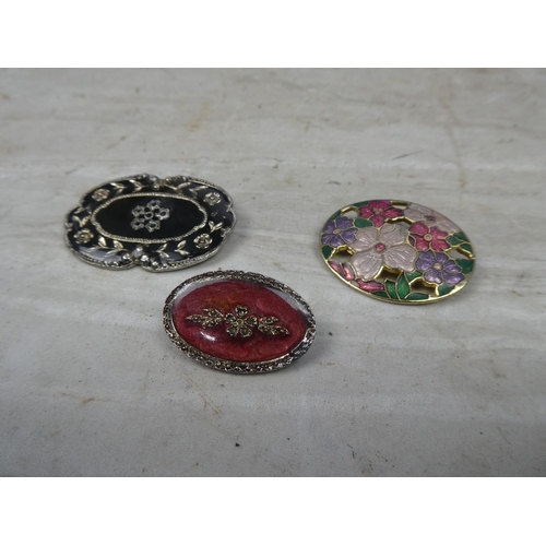 156 - Three floral patterned brooches.