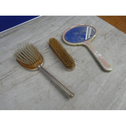 121 - A vintage dressing table mirror and two brushes.